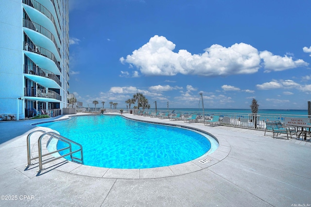 pool featuring a water view and a patio