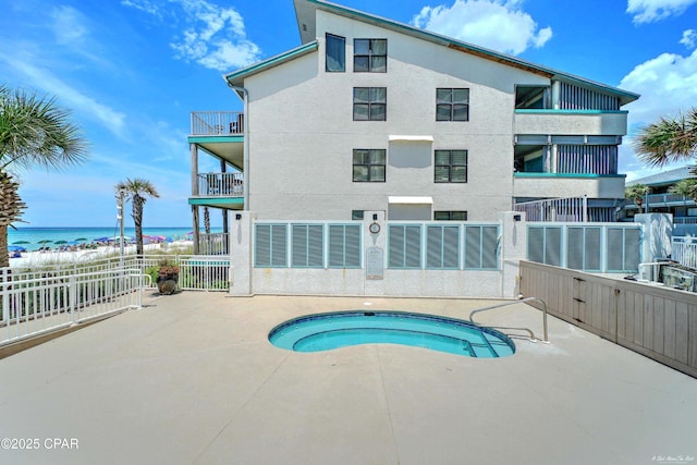 view of pool with a water view, a hot tub, and fence