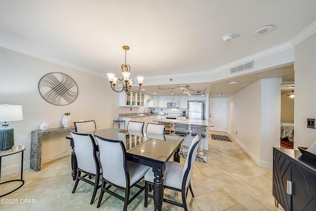 dining room featuring baseboards, a notable chandelier, visible vents, and crown molding