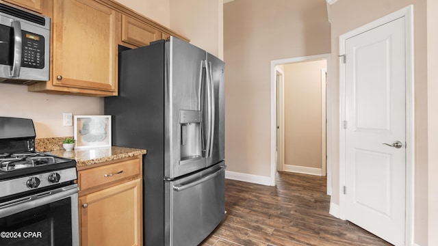 kitchen with light stone countertops, stainless steel appliances, and dark hardwood / wood-style floors