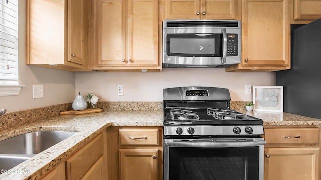 kitchen with light stone counters, sink, and appliances with stainless steel finishes