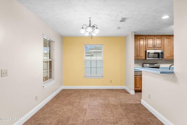 kitchen featuring kitchen peninsula, a textured ceiling, ceiling fan with notable chandelier, sink, and light tile patterned floors