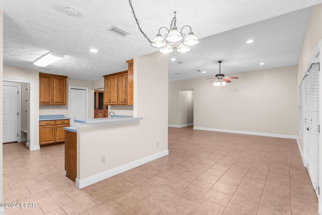 kitchen with kitchen peninsula, appliances with stainless steel finishes, a textured ceiling, and light tile patterned floors