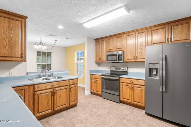 kitchen featuring sink, hanging light fixtures, a notable chandelier, a textured ceiling, and appliances with stainless steel finishes