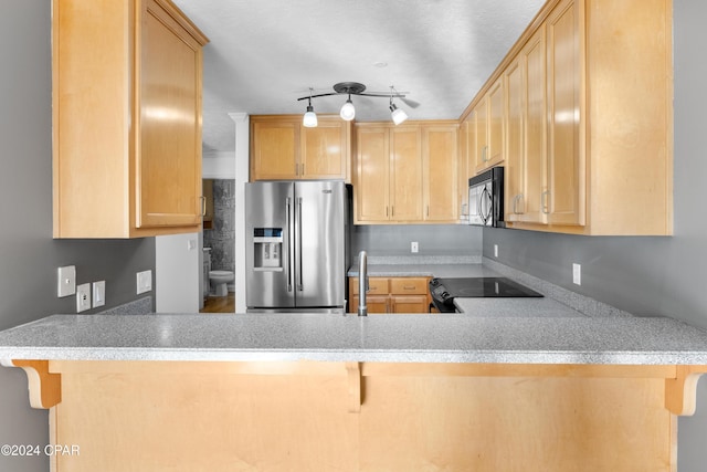 kitchen featuring a kitchen bar, light brown cabinetry, and black appliances