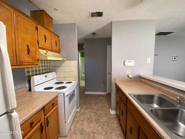 kitchen with a textured ceiling, white appliances, backsplash, and sink