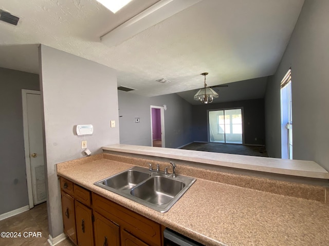 kitchen featuring kitchen peninsula, sink, a chandelier, and a textured ceiling