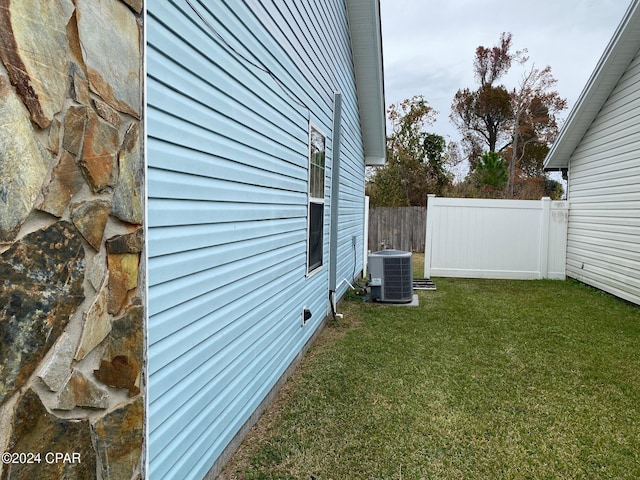 view of side of home with a yard and central AC