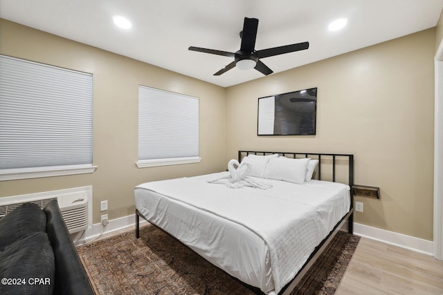 bedroom with ceiling fan, wood-type flooring, and a wall mounted AC