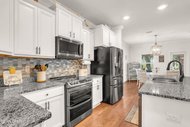 kitchen featuring white cabinetry, sink, stainless steel appliances, and decorative light fixtures