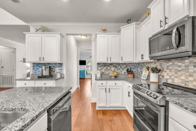 kitchen with white cabinets, stainless steel appliances, light hardwood / wood-style flooring, and tasteful backsplash