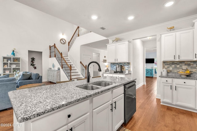 kitchen featuring dishwasher, sink, backsplash, an island with sink, and white cabinets