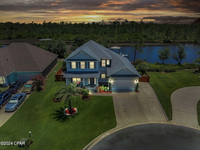 view of front of property with a water view, a garage, and a lawn