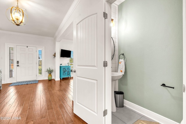 entrance foyer with an inviting chandelier, wood-type flooring, and ornamental molding