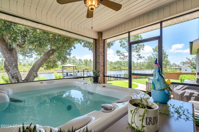 sunroom featuring ceiling fan, a water view, and a hot tub