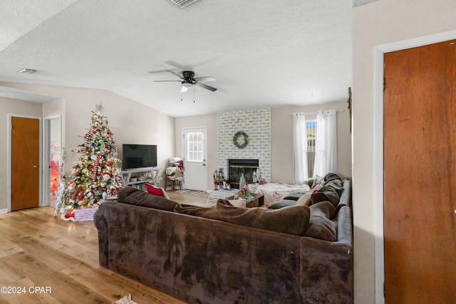 7707 Shadow Bay Dr, Panama City, FL 32404 - living room with lofted ceiling, ceiling fan, a fireplace, a textured ceiling, and light wood-type flooring