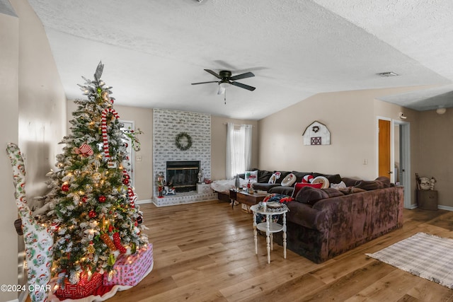 7707 Shadow Bay Dr, Panama City, FL 32404 - living room featuring lofted ceiling, hardwood / wood-style flooring, ceiling fan, a fireplace, and a textured ceiling
