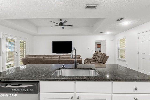 kitchen featuring stainless steel dishwasher, a textured ceiling, a raised ceiling, sink, and white cabinetry