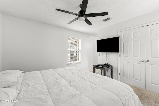 carpeted bedroom featuring a textured ceiling, a closet, and ceiling fan