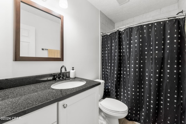 bathroom with toilet, vanity, a textured ceiling, and walk in shower