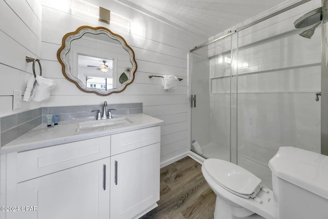 bathroom with vanity, a shower with door, wood-type flooring, toilet, and wood walls