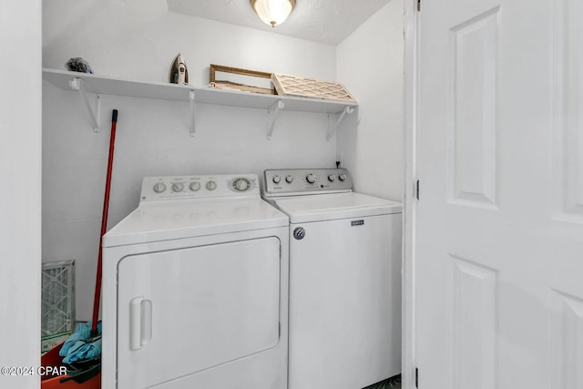 clothes washing area with washer and clothes dryer and a textured ceiling