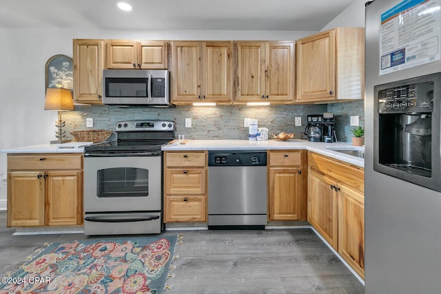 kitchen featuring backsplash, light brown cabinets, stainless steel appliances, and wood-type flooring