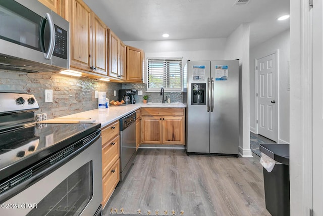 kitchen featuring backsplash, light hardwood / wood-style floors, sink, and stainless steel appliances