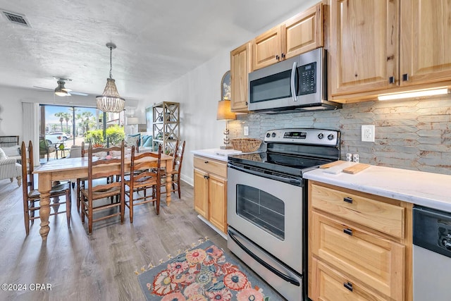 kitchen featuring hardwood / wood-style floors, pendant lighting, stainless steel appliances, and light brown cabinetry