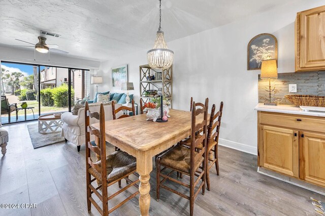 dining space with ceiling fan with notable chandelier and light wood-type flooring