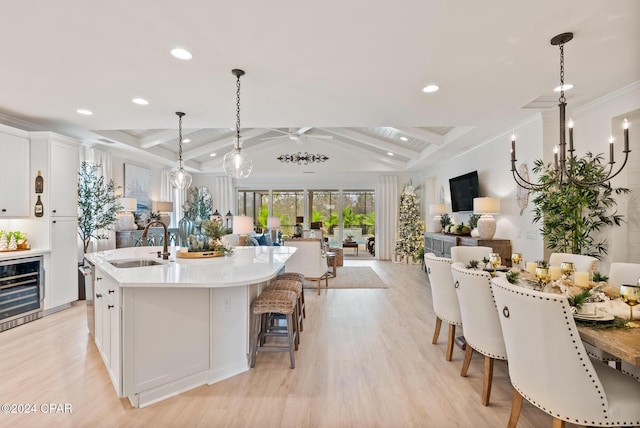 kitchen with pendant lighting, white cabinetry, sink, and beverage cooler