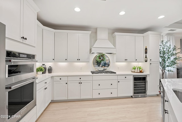 kitchen with wine cooler, white cabinetry, custom range hood, and appliances with stainless steel finishes