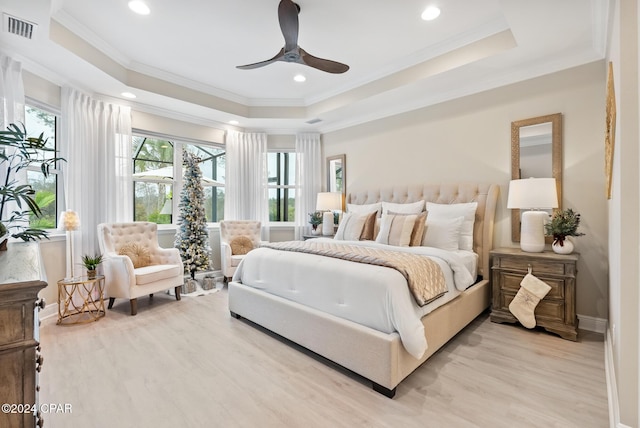 bedroom with light hardwood / wood-style floors, a raised ceiling, ceiling fan, and crown molding