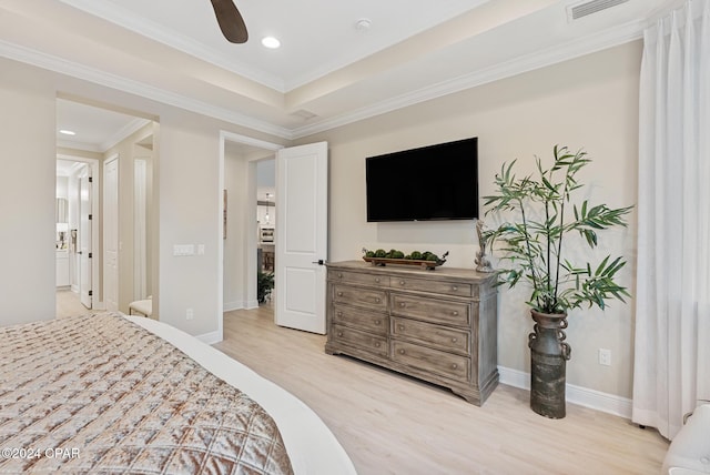 bedroom with a tray ceiling, ceiling fan, crown molding, and light wood-type flooring