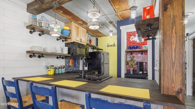 kitchen with sink, light brown cabinetry, stainless steel fridge, and a breakfast bar