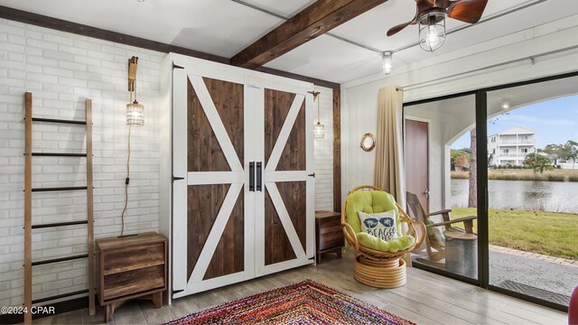 bedroom featuring brick wall, beam ceiling, access to outside, and a water view