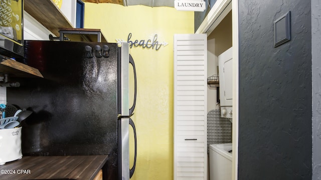 kitchen featuring stacked washer / dryer and stainless steel fridge