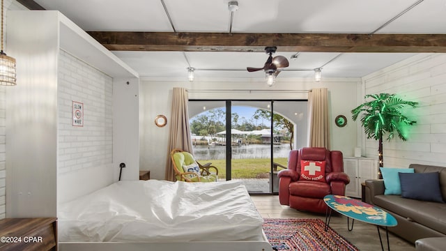 bedroom featuring a water view, beamed ceiling, access to exterior, and hardwood / wood-style floors