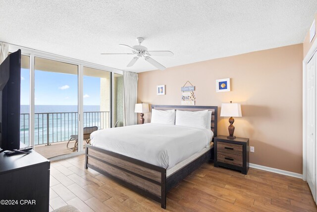 bedroom featuring expansive windows, access to exterior, a textured ceiling, and light hardwood / wood-style flooring