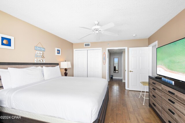 bedroom featuring ceiling fan, a textured ceiling, dark hardwood / wood-style flooring, and a closet