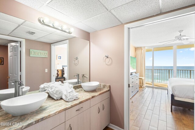 bathroom featuring vanity, hardwood / wood-style floors, a wall of windows, and a drop ceiling