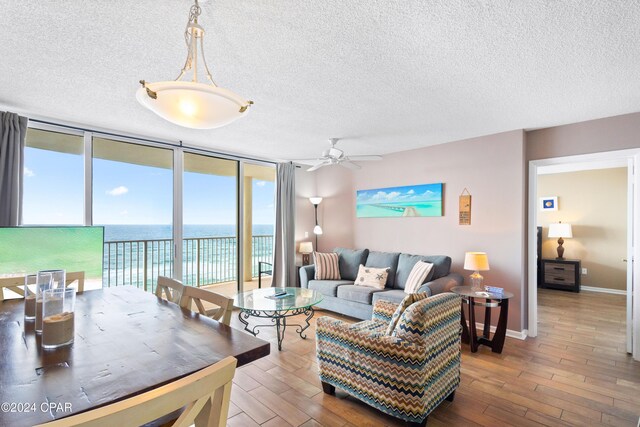 living room featuring a water view, floor to ceiling windows, hardwood / wood-style floors, and a textured ceiling