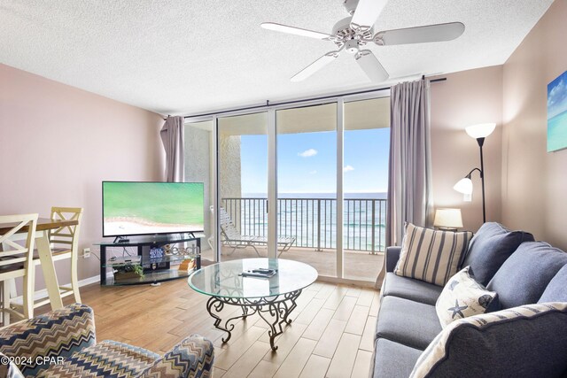 living room with expansive windows, ceiling fan, hardwood / wood-style floors, and a textured ceiling