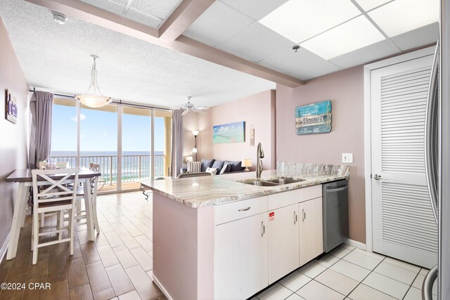 kitchen featuring sink, dishwasher, a water view, decorative light fixtures, and kitchen peninsula