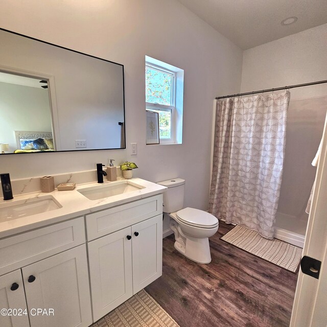 full bathroom featuring hardwood / wood-style floors, vanity, toilet, and shower / tub combo with curtain