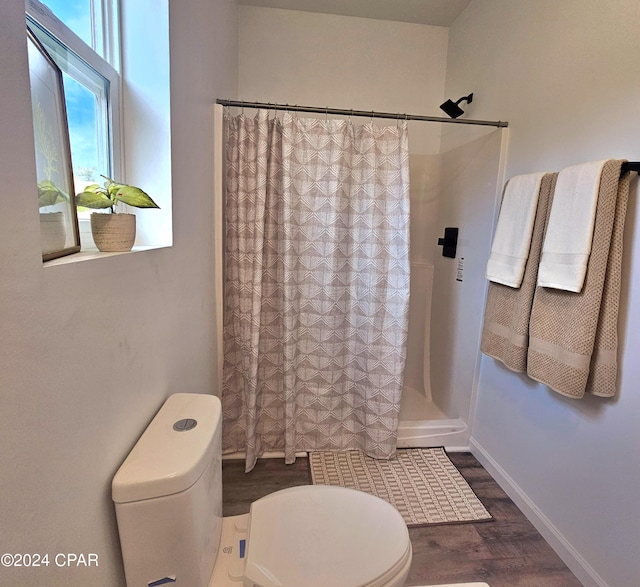 bathroom featuring hardwood / wood-style floors, toilet, and curtained shower