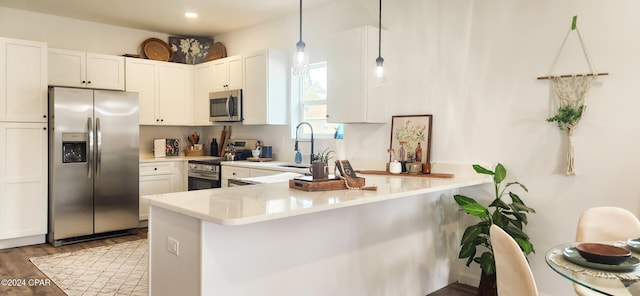 kitchen with pendant lighting, white cabinetry, kitchen peninsula, and appliances with stainless steel finishes