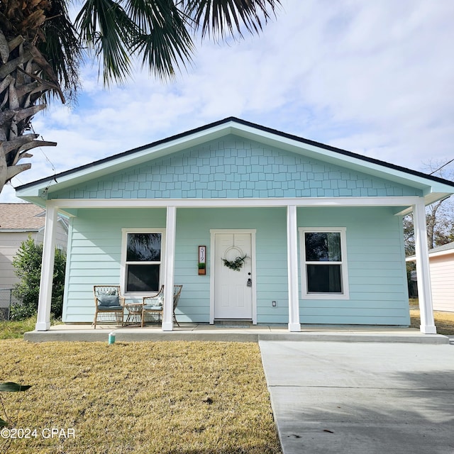 bungalow-style house featuring covered porch and a front yard