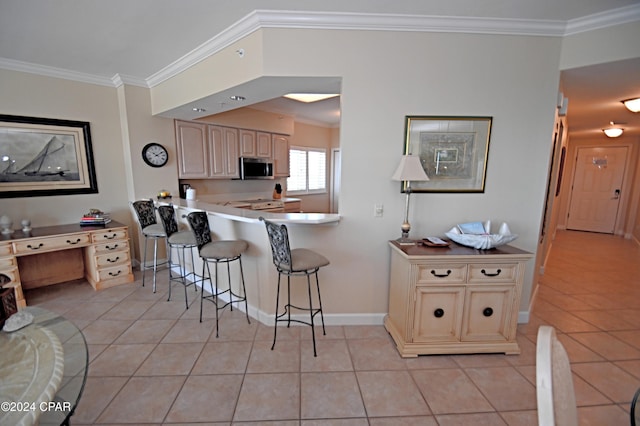 kitchen featuring light tile patterned floors, a kitchen breakfast bar, light countertops, stainless steel microwave, and crown molding