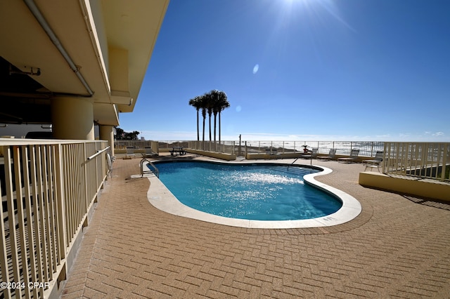 community pool with a patio area and fence